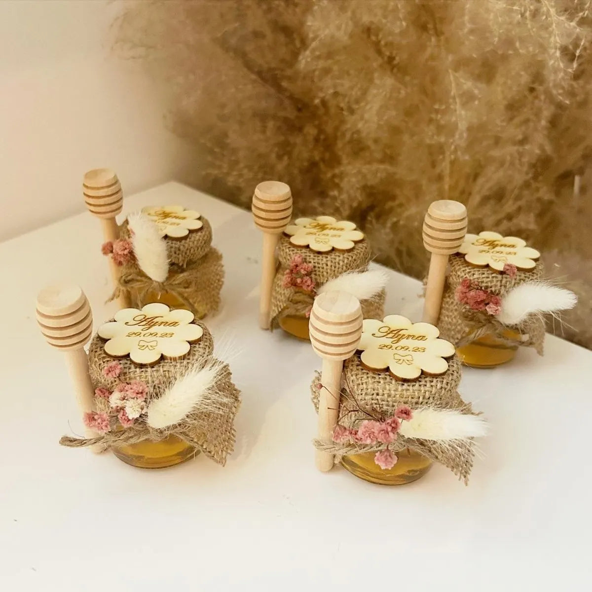 Floa-Honigglas als personalisiertes Gastgeschenk für Hochzeit, Taufe und Kommunion, dekoriert mit Holzlöffel, Blumen und natürlicher Deko