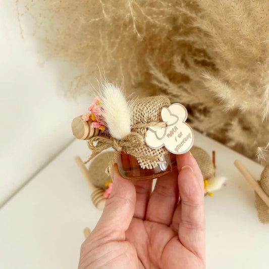 Zauberhaftes Honigglas als personalisiertes Gastgeschenk zur Taufe, zum Geburtstag und zur Kommunion, elegant dekoriert mit Holzlöffel und Blumen