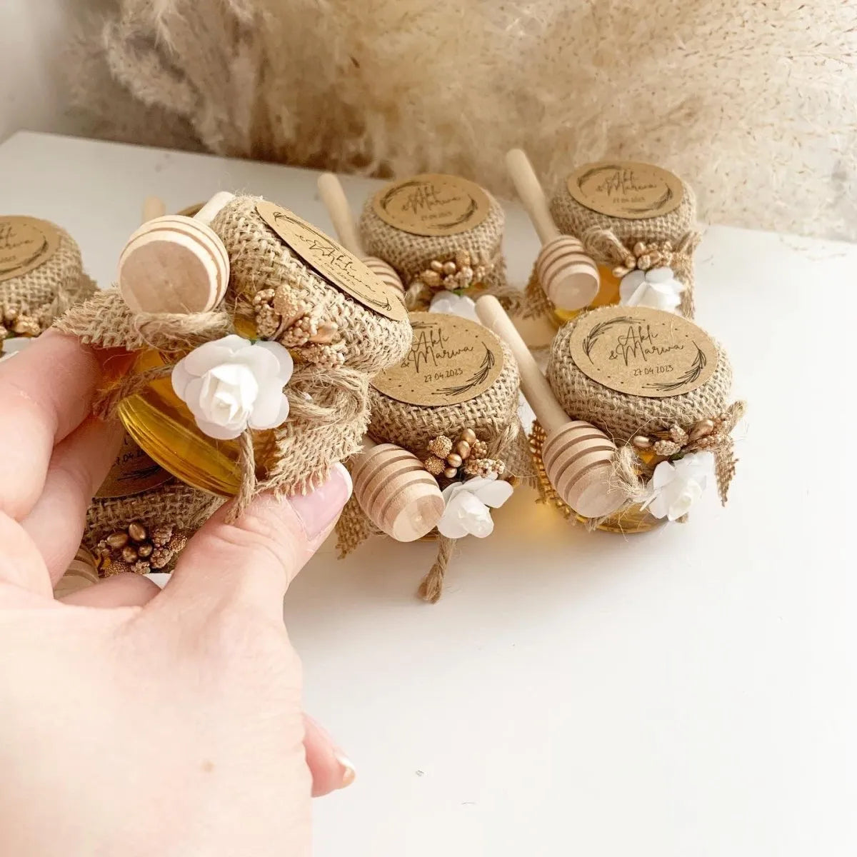 Festliches Honigglas als personalisiertes Gastgeschenk für Hochzeit, Taufe und Kommunion, elegant dekoriert mit Holzlöffel und natürlicher Deko