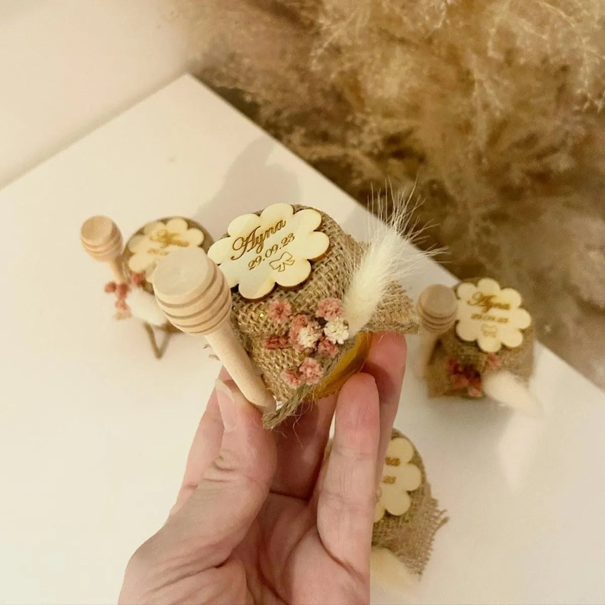 Floa-Honigglas als personalisiertes Gastgeschenk für Hochzeit, Taufe und Kommunion, dekoriert mit Holzlöffel, Blumen und natürlicher Deko