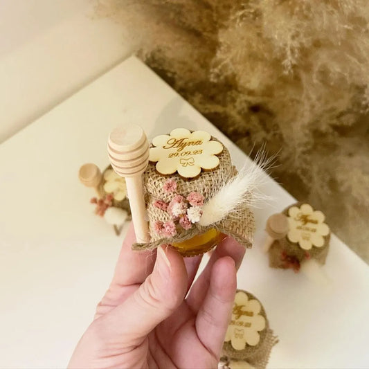 Floa-Honigglas als personalisiertes Gastgeschenk für Hochzeit, Taufe und Kommunion, dekoriert mit Holzlöffel, Blumen und natürlicher Deko
