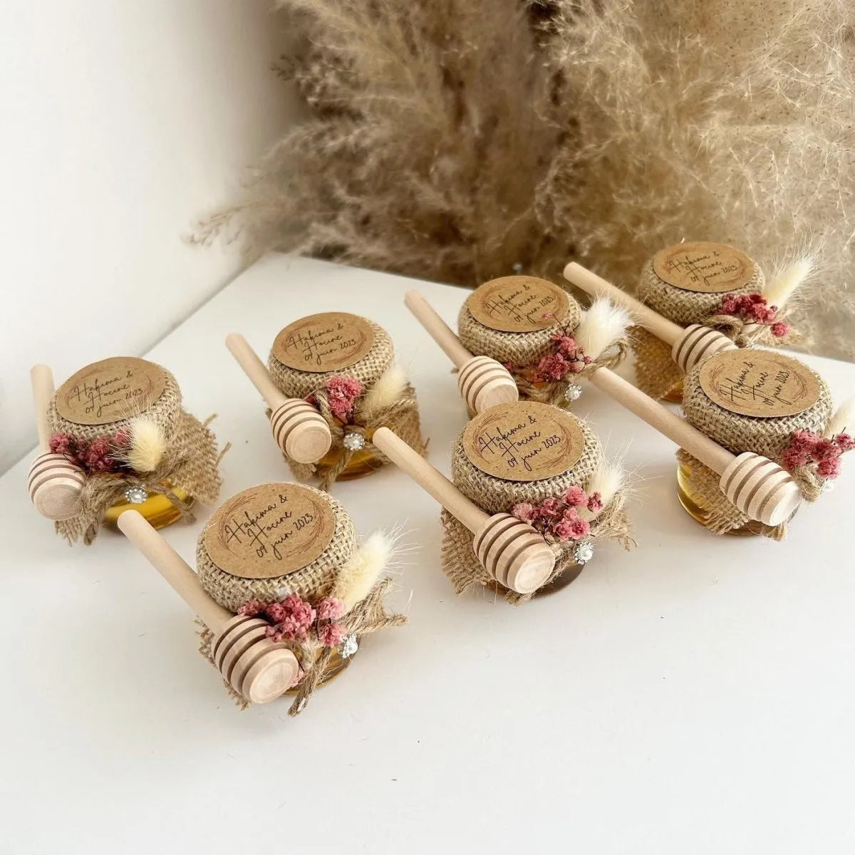 Himbeer-Honigglas als personalisiertes Gastgeschenk für Hochzeit, Taufe und Kommunion, dekoriert mit Trockenblumen, Holzlöffel und framboisefarbenen Details