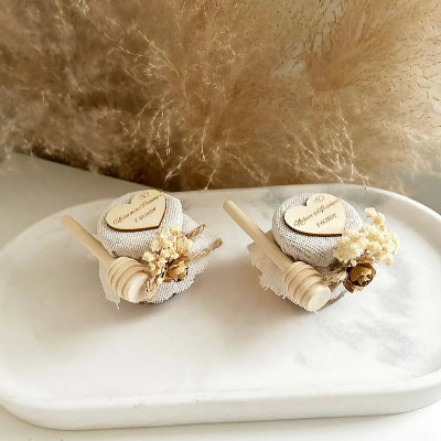 Honigglas des Brautpaares als personalisiertes Gastgeschenk zur Hochzeit, mit Herzanhänger, Holzlöffel und eleganter Dekoration