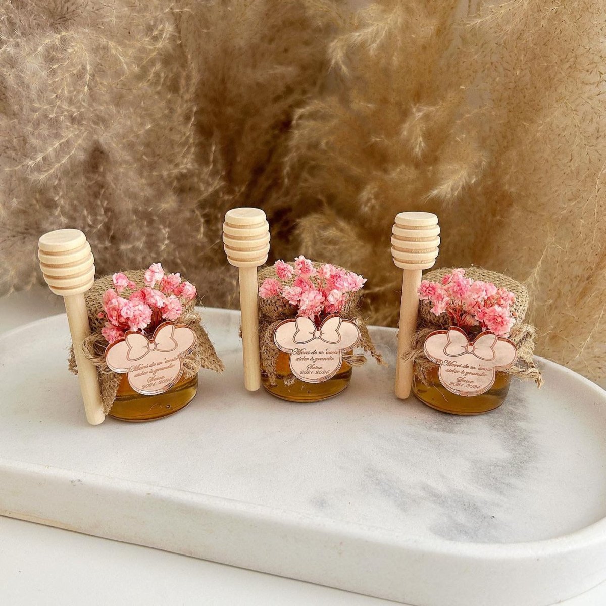 Honigglas Mimi als personalisiertes Gastgeschenk zur Taufe und Kommunion, dekoriert mit Blumen, Schleife und Holzlöffel