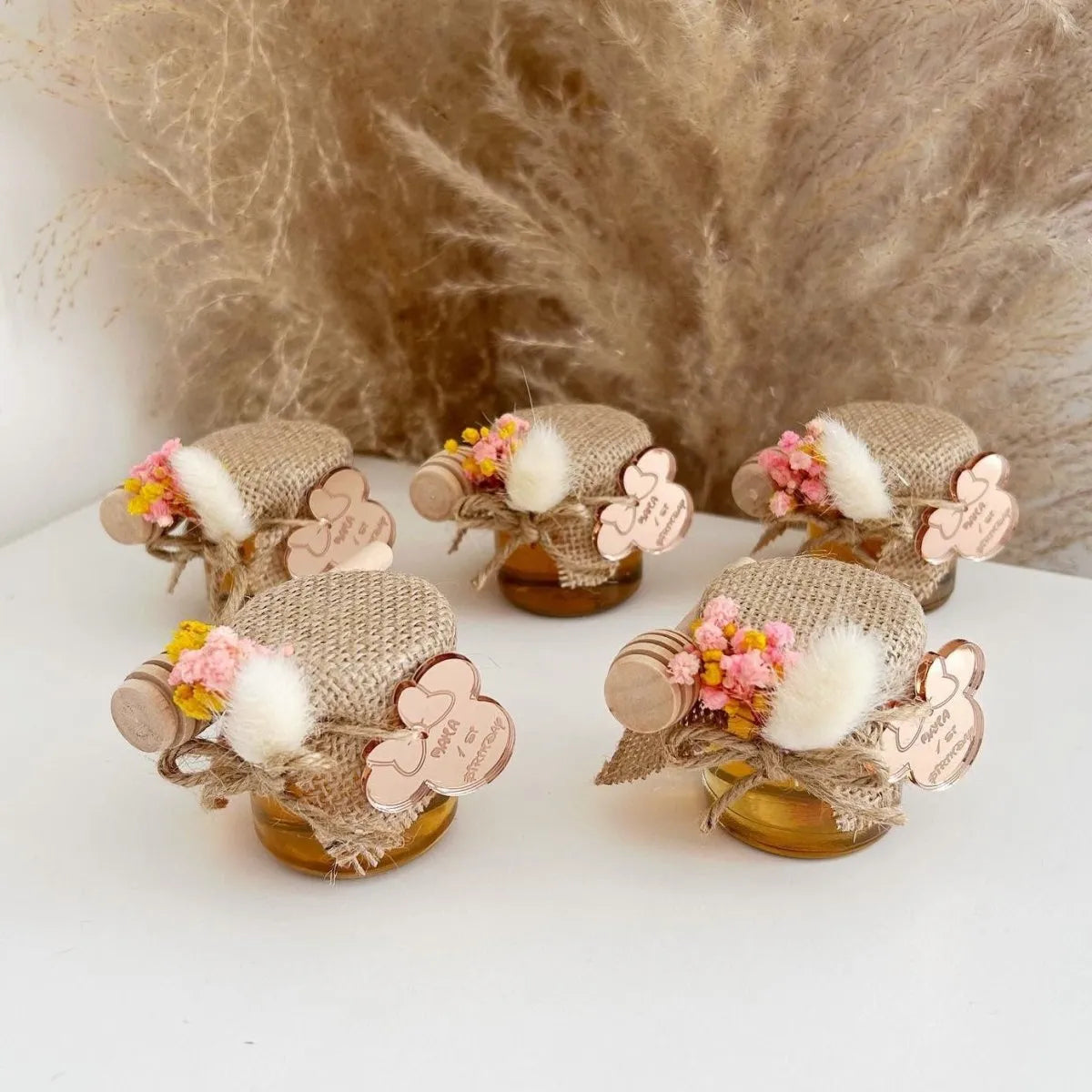 Zauberhaftes Honigglas als personalisiertes Gastgeschenk zur Taufe, zum Geburtstag und zur Kommunion, elegant dekoriert mit Holzlöffel und Blumen