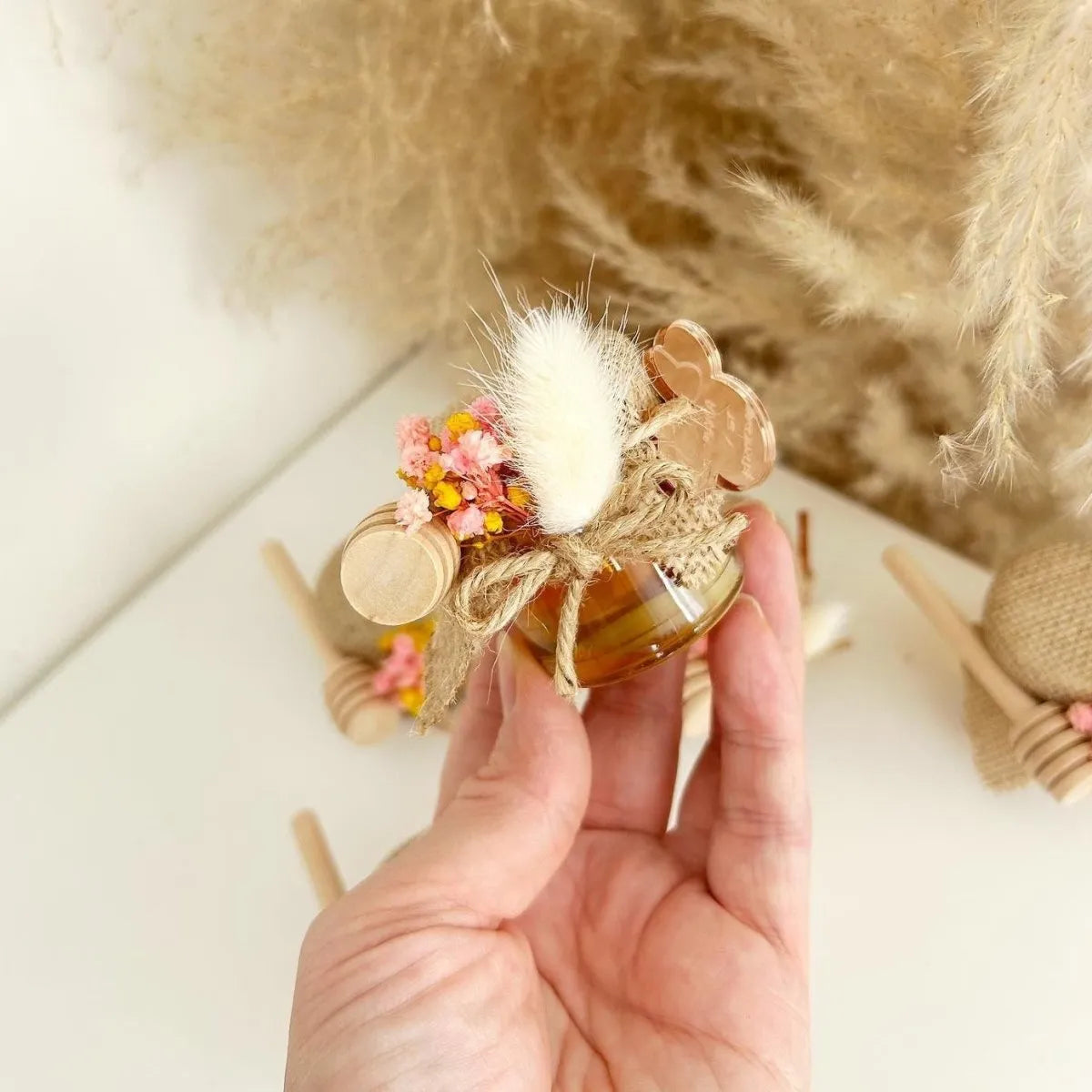 Zauberhaftes Honigglas als personalisiertes Gastgeschenk zur Taufe, zum Geburtstag und zur Kommunion, elegant dekoriert mit Holzlöffel und Blumen