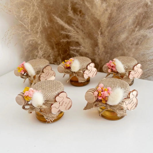 Zauberhaftes Honigglas als personalisiertes Gastgeschenk zur Taufe, zum Geburtstag und zur Kommunion, elegant dekoriert mit Holzlöffel und Blumen
